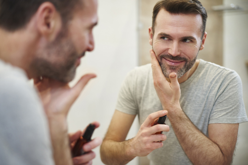 Smiling man applying beauty product on his face