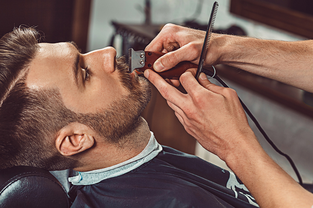 A man getting his beard trimmed at a barber shop