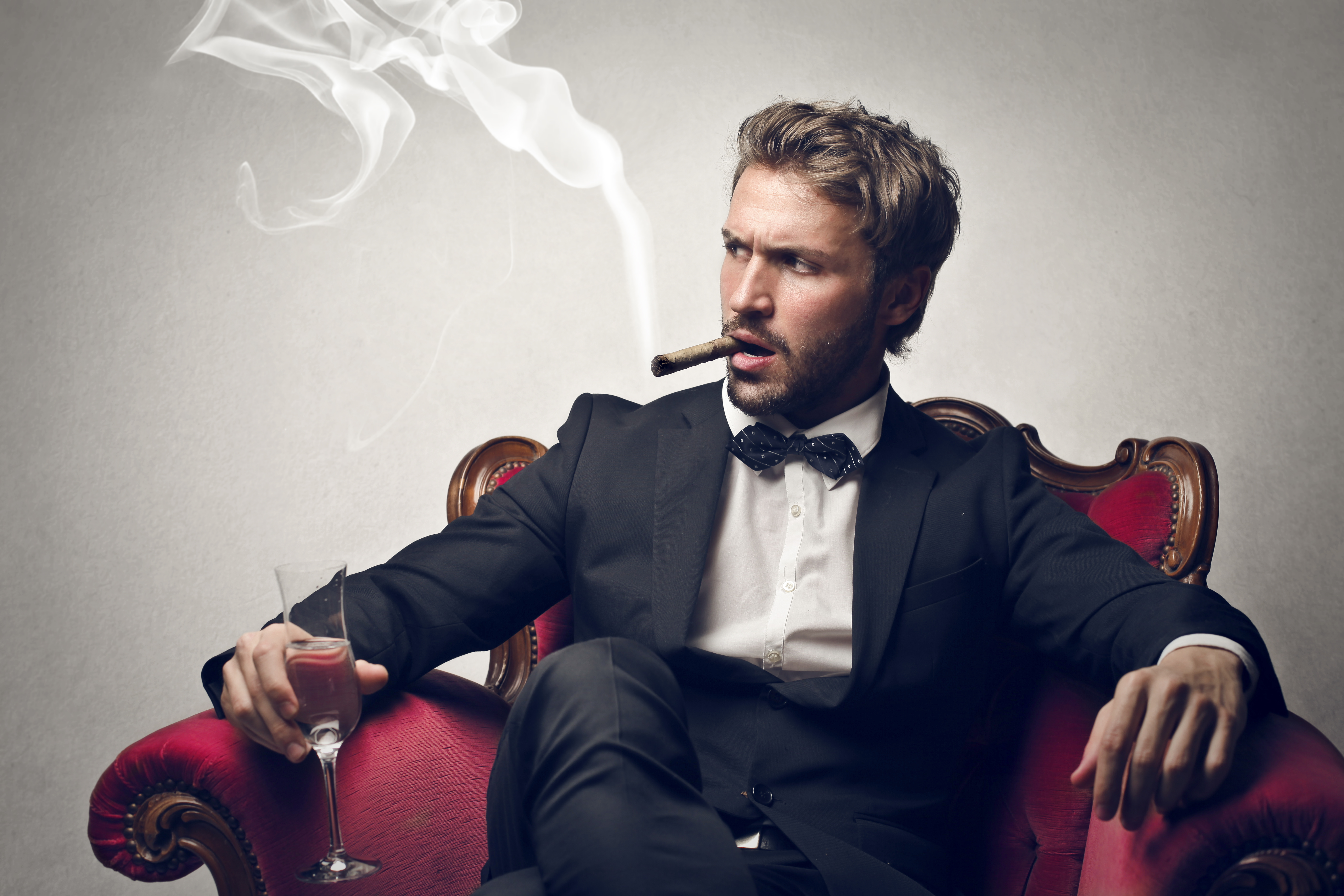 Bearded man sitting with cigar and champagne