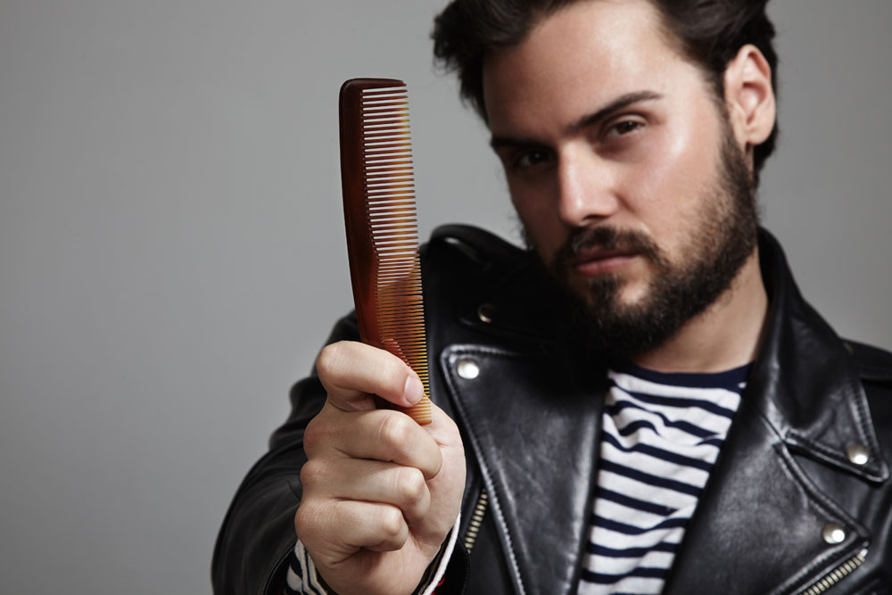 Bearded guy in leather jacket holding comb
