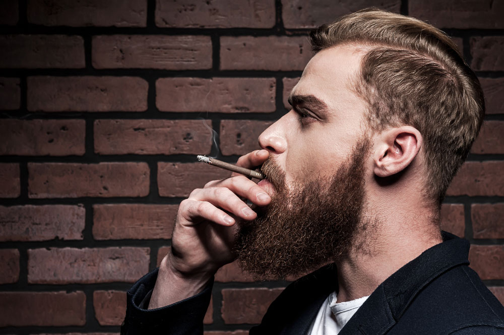 Bearded man smoking brown cigarillo