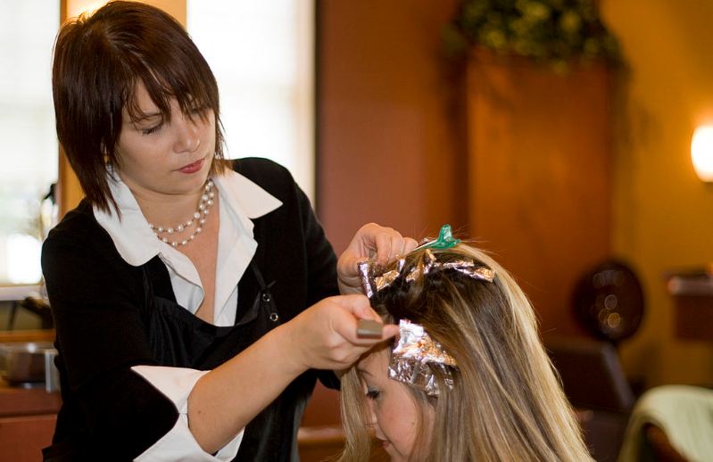 A professional hairstylist coloring the hair of her client.
