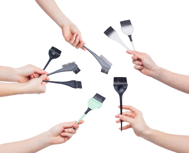 Set of hands holding various brushes for hair dying isolated on white background